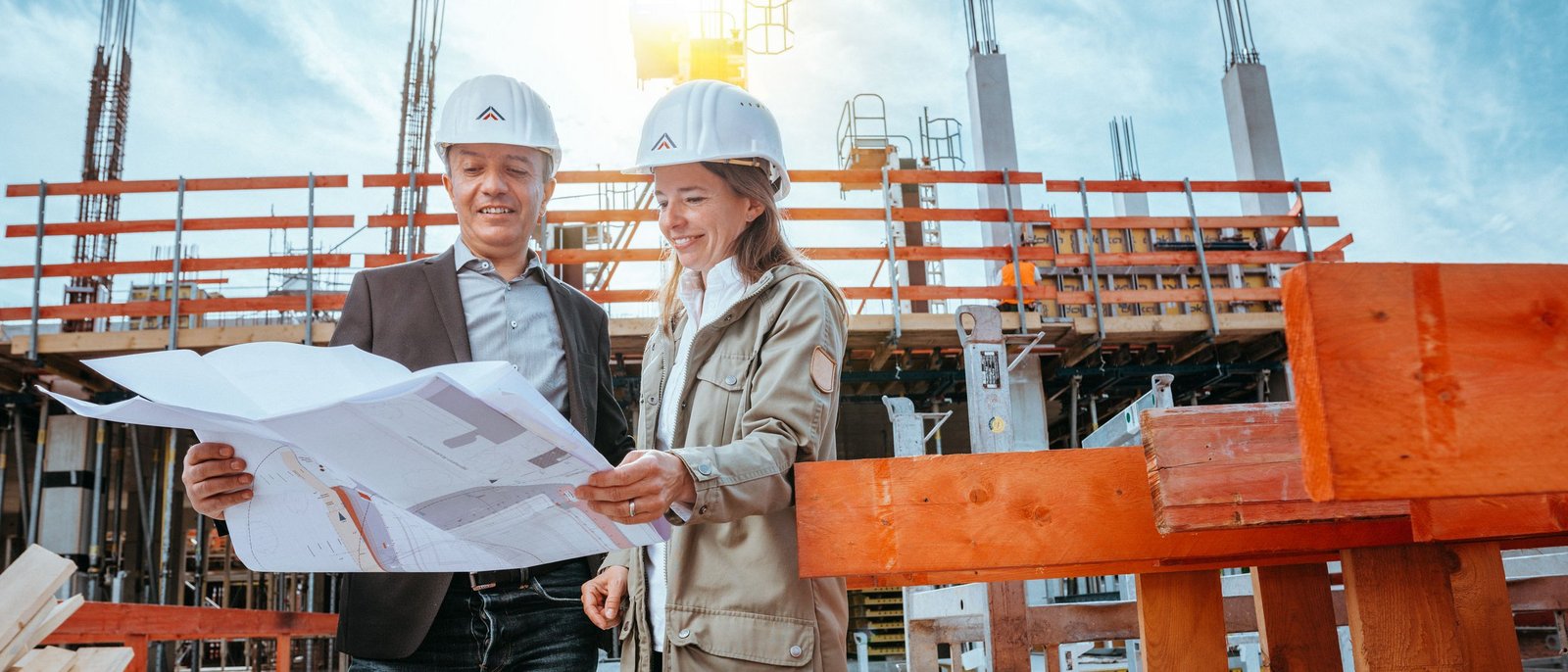 Zwei Menschen prüfen einen Bauplan auf einer Baustelle