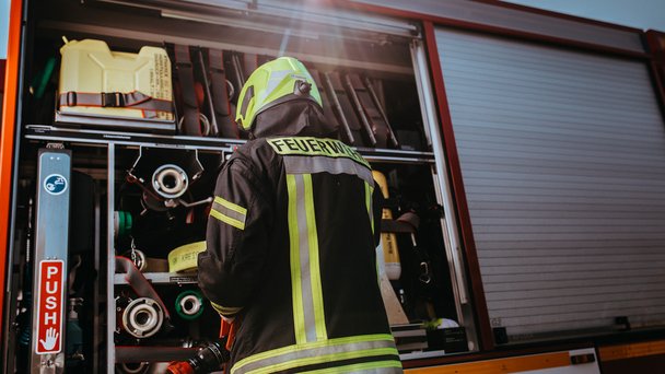 Ein Feuerwehrmann steht vor dem Einsatzfahrzeug