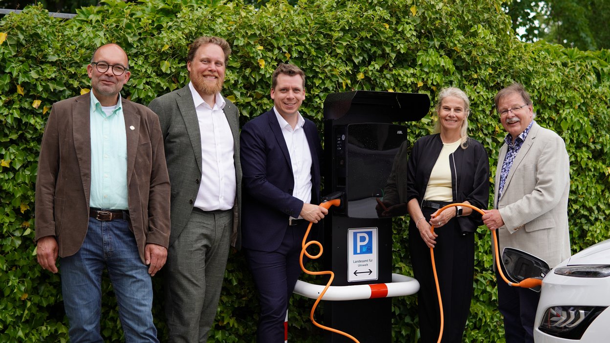 Fünf Personen stehen vor einer Ladesäule für E-Autos. 