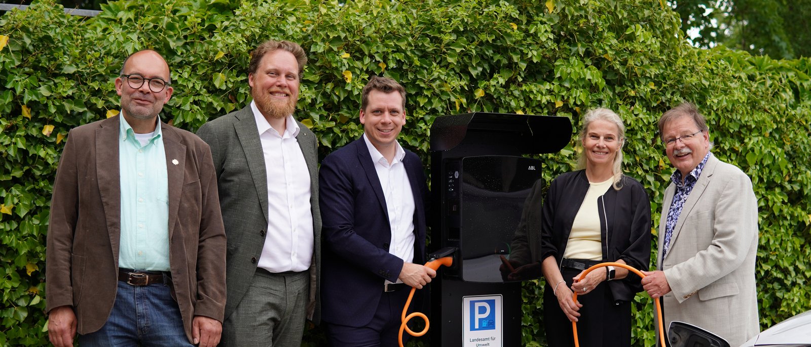 Fünf Personen stehen vor einer Ladesäule für E-Autos. 