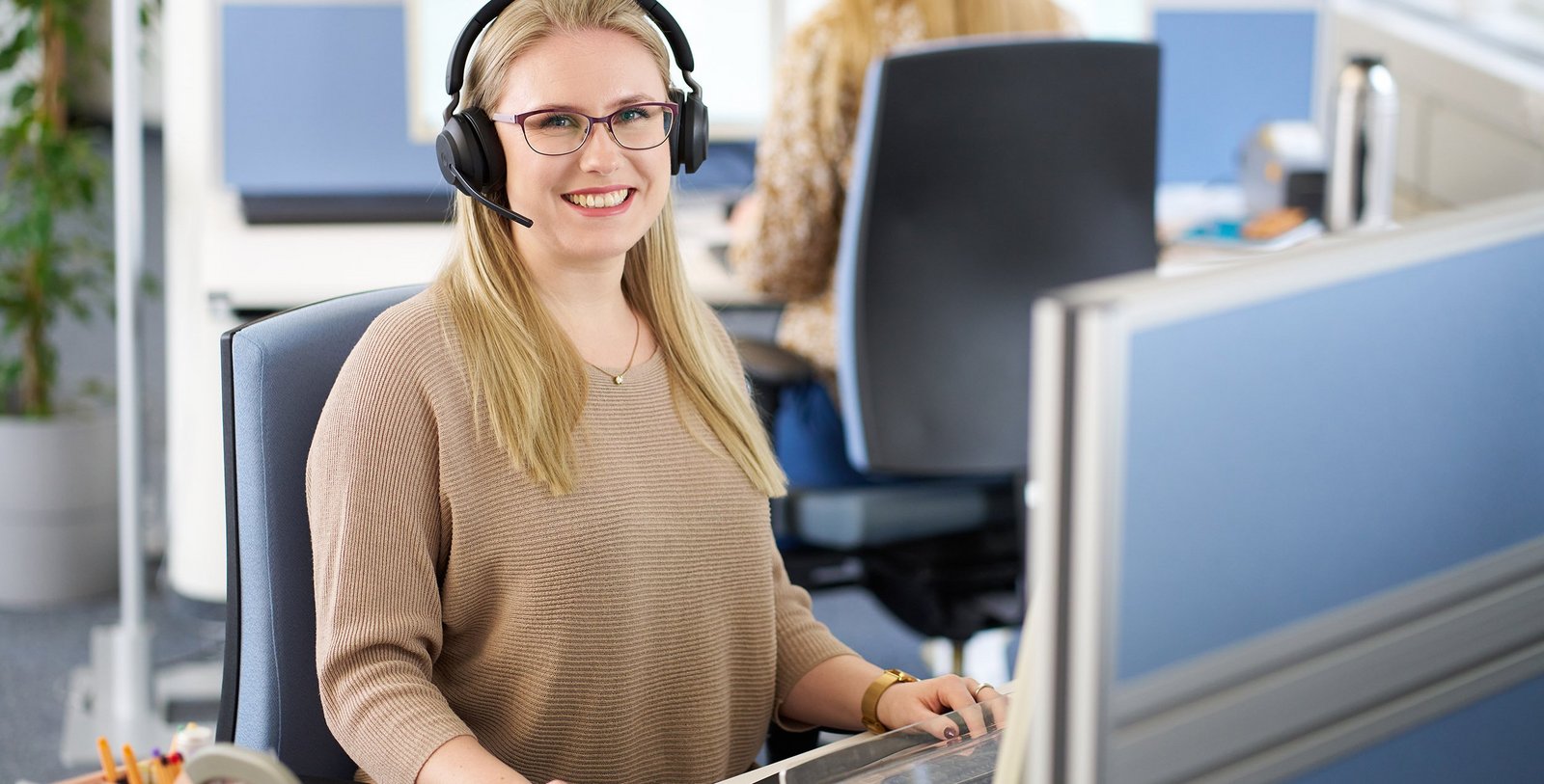 Eine freundliche Frau mit Headset nimmt Kundenanfragen telefonisch entgegen