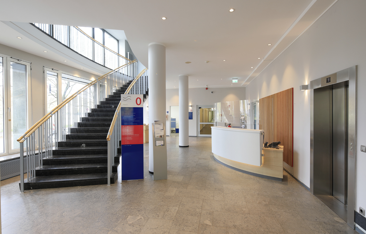 Eine Treppe führt ins erste Obergeschoss der GMSH-Zentrale. Im Vordergrund ist der Empfang zu sehen.