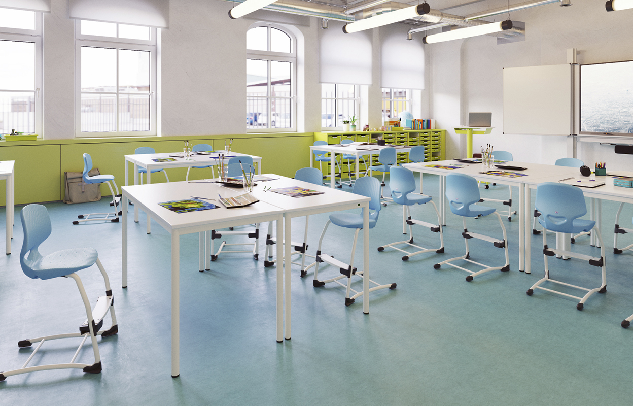 Ein Klassenzimmer mit blauen Stühlen und weißen Tischen.