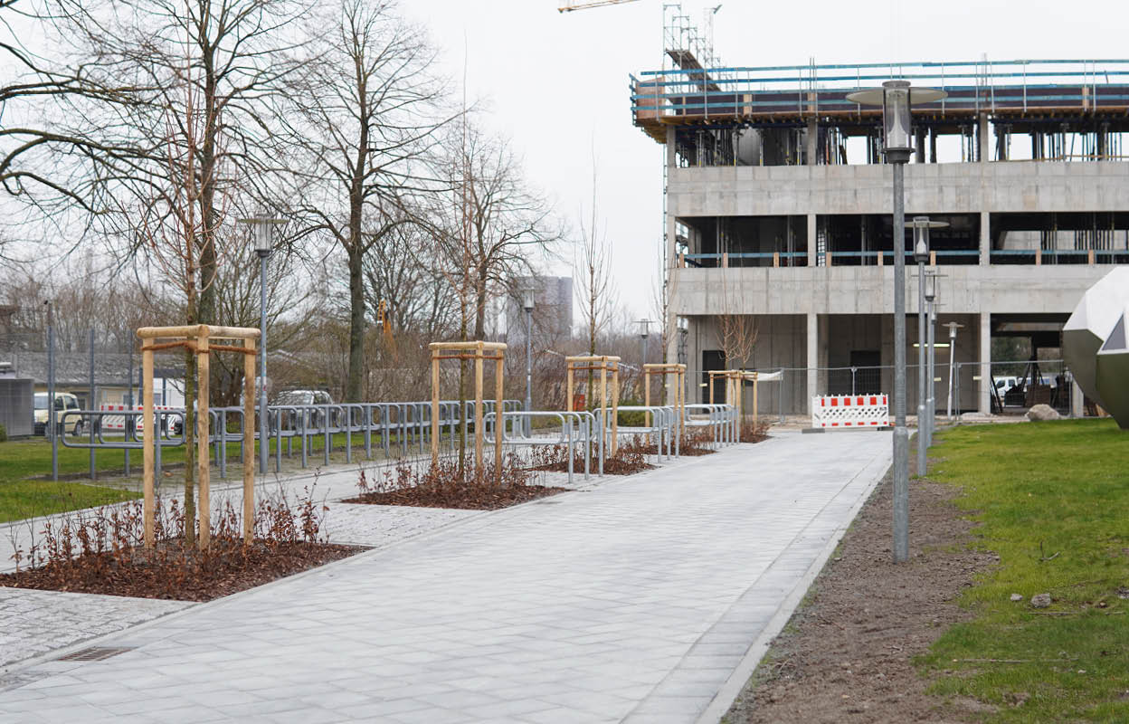 ein Weg mit Fahrradbügeln führt auf ein Gebäude zu